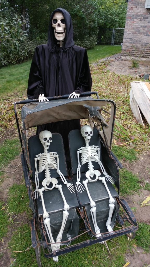 twin skeletons being pushed in a double stroller with larger skeleton